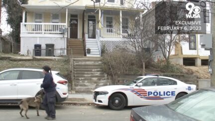 A K-9 officer walks past the D.C. home where a handyman was found decapitated.
