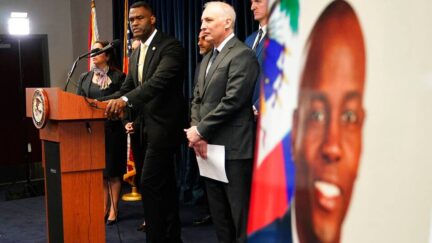 An image of Haitian President Jovenel Moïse, right, is displayed as Markenzy Lapointe, U.S. Attorney for the Southern District of Florida, left, speaks as Matthew Olsen, Assistant Attorney General for National Security, looks on during a news conference, Tuesday, Feb. 14, 2023, in Miami. U.S. authorities have arrested four more people in the slaying of Haitian President Jovenel Moïse, including the owner of a Miami-area security company that hired former soldiers from Colombia for the mission. (AP Photo/Lynne Sladky)